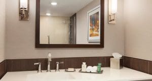 A picture of the faucet in the washroom with large mirror